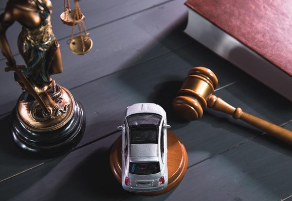 statue of justice, gavel and car on a wooden background. trial